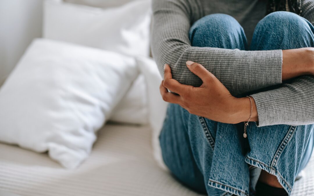 Black woman sat on bed stressed